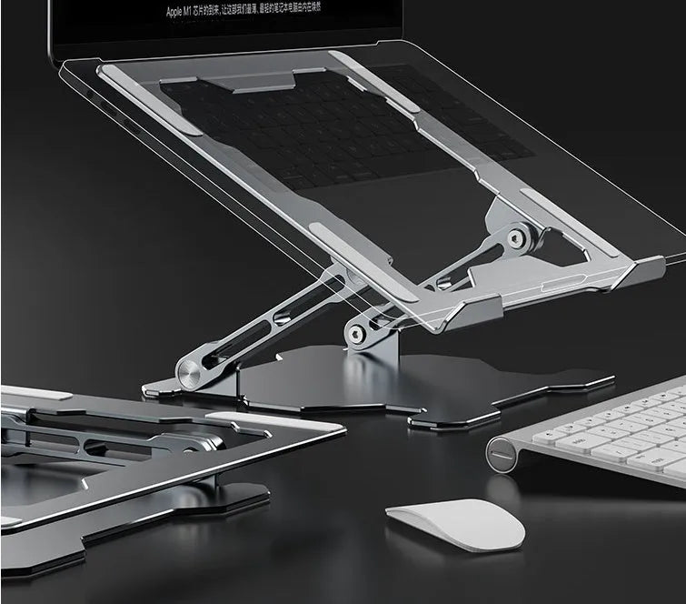 Grey aluminium laptop stand folded flat next to an open laptop, showing its adjustable angle and hollow design.