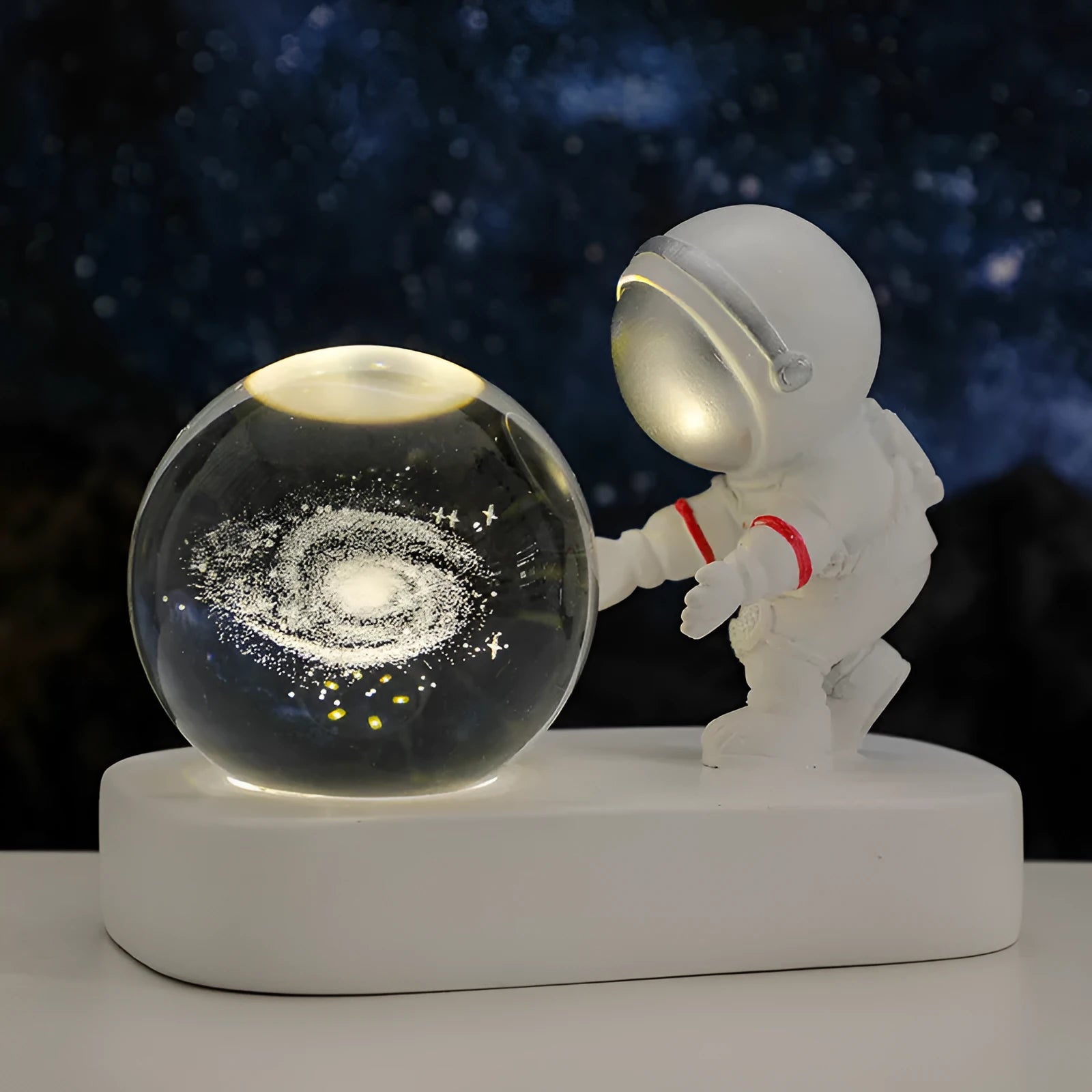 Small clear resin ball night light with glowing astronaut and galaxy scene inside on dark surface