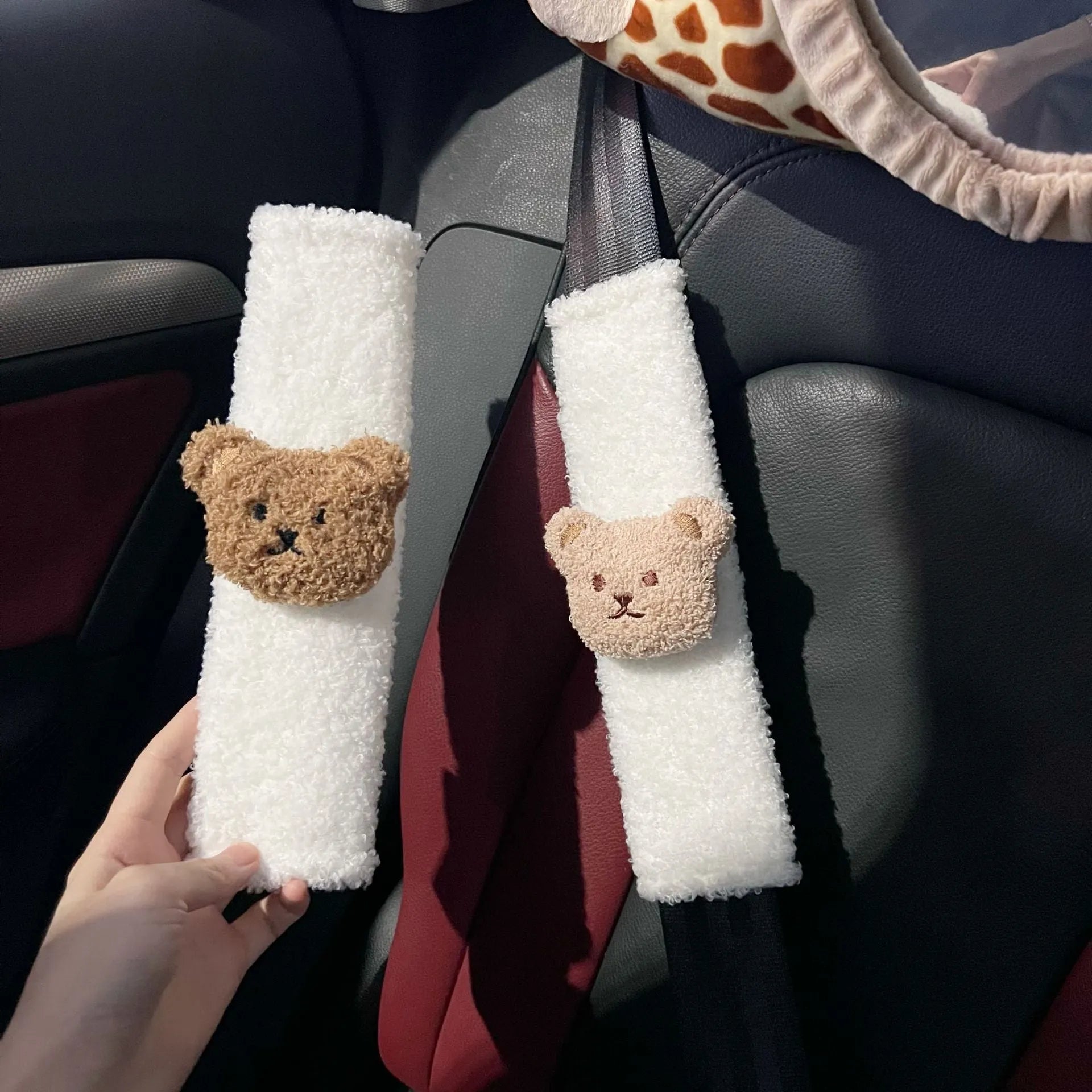 Close-up of a khaki-coloured plush bear seat belt cover on a car seat strap.