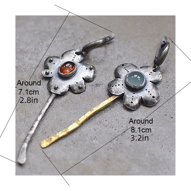 A pair of long retro-style earrings with a geometric floral shape in an asymmetric two-tone colour finish.