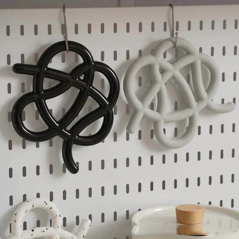 Ceramic heat proof mat in irregular shape on a table, shown in bright black colour.