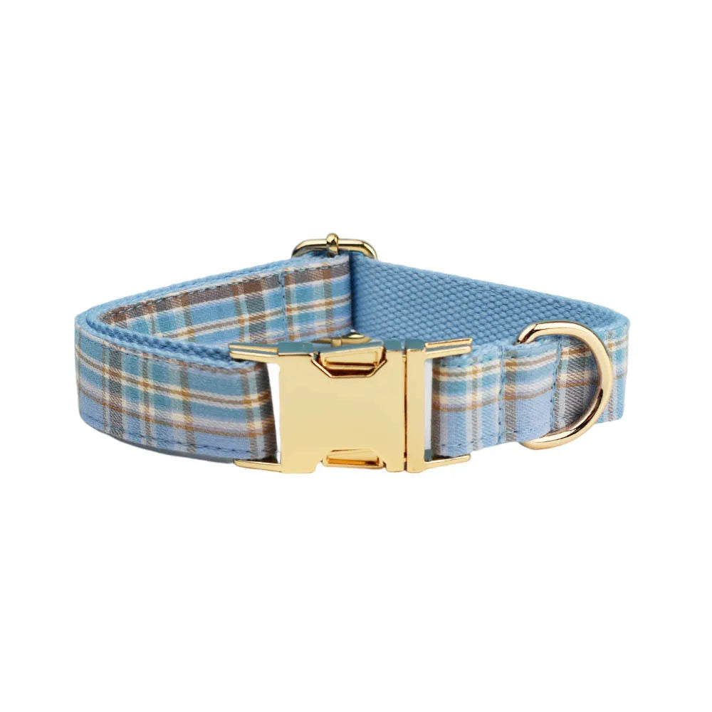Sky blue grid forest pattern dog collar, leash, bow, and vest four-piece pet set laid out flat.