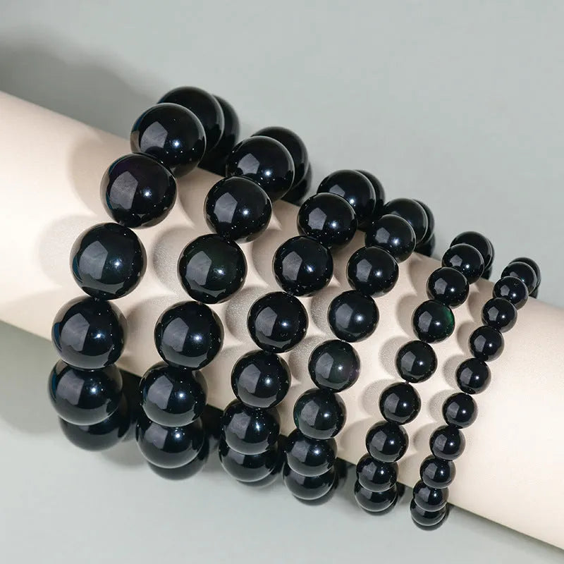 Hand-woven round obsidian crystal bracelet for couples on wrist, showing ethnic style and adjustable fit.
