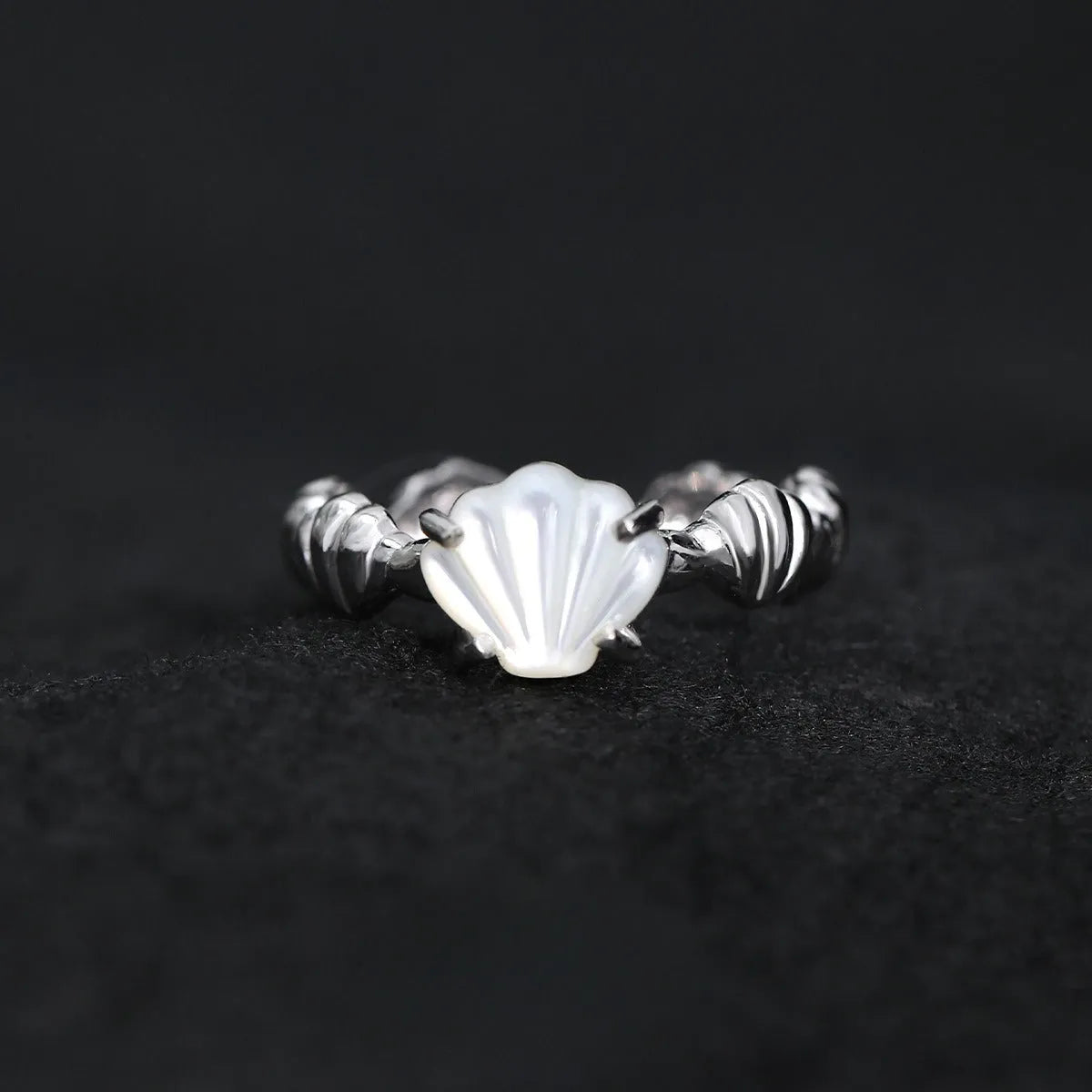 Women's silver ring with shell design and Tiger Eye stone on an adjustable band.