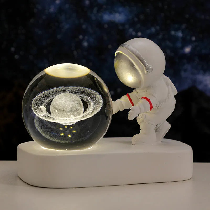 Small clear resin ball night light with glowing astronaut and galaxy scene inside on dark surface