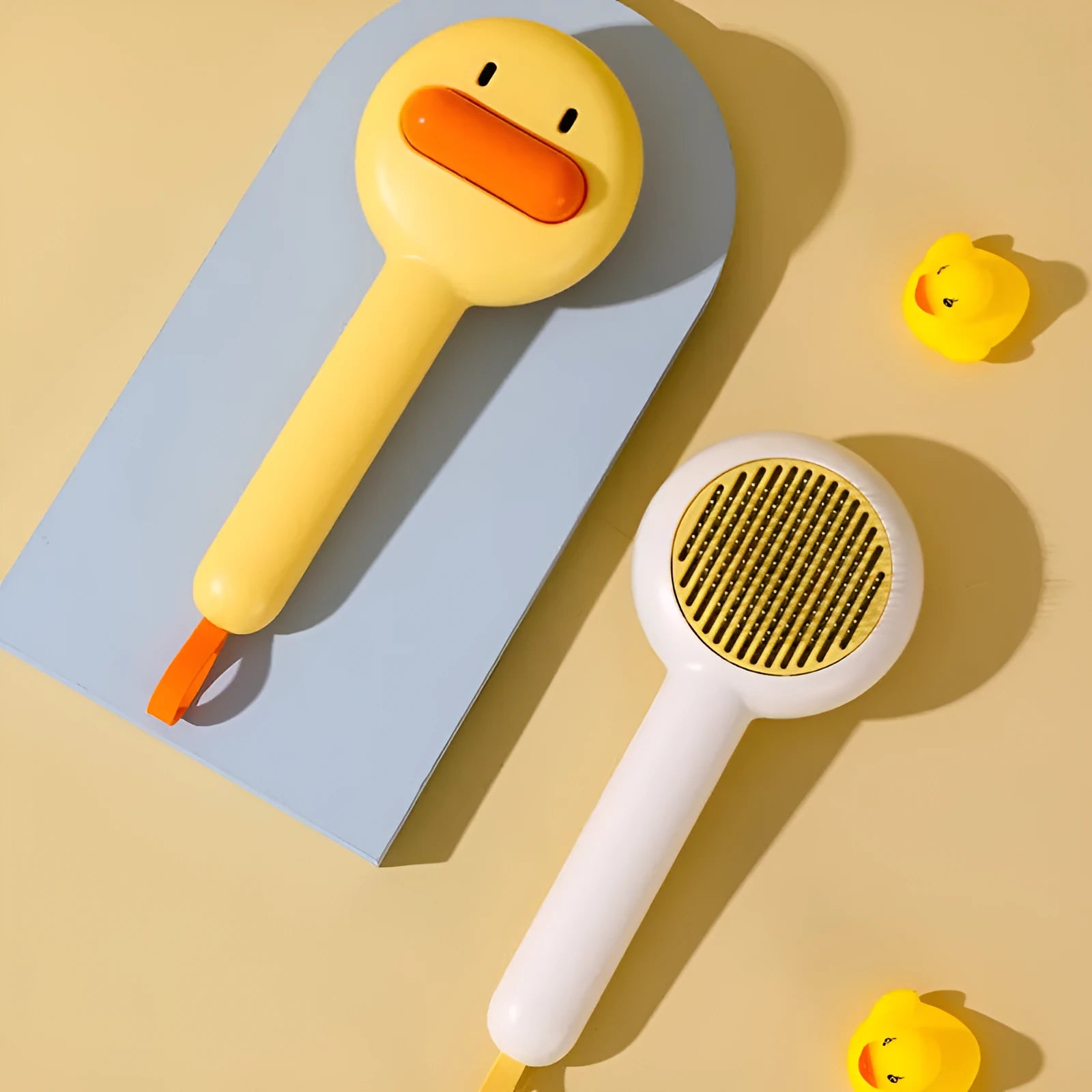Small yellow duck-shaped pet grooming comb with open section design and needle teeth for cat and dog fur removal