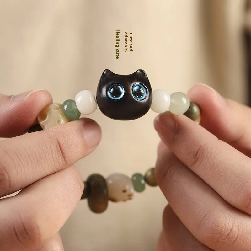 Hand-woven bracelet with bodhi seeds, jade, and wood featuring cartoon cat charm in multiple colour options