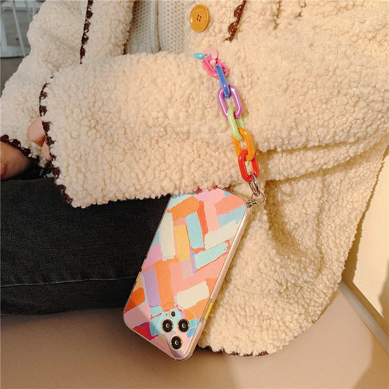 Pink iPhone case with a graffiti design and a white wrist strap attached.