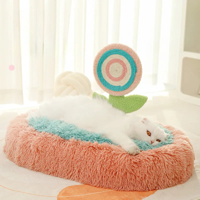 Pink elliptical plush cat bed with a removable, washable cover on a wooden floor.