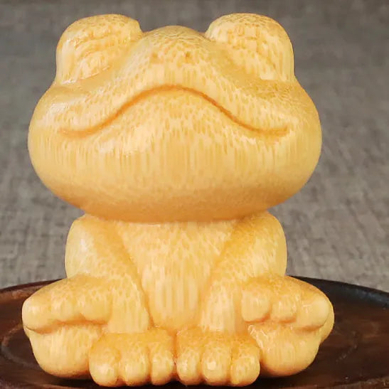 Small smiling frog ornament carved from solid bamboo on a plain background.