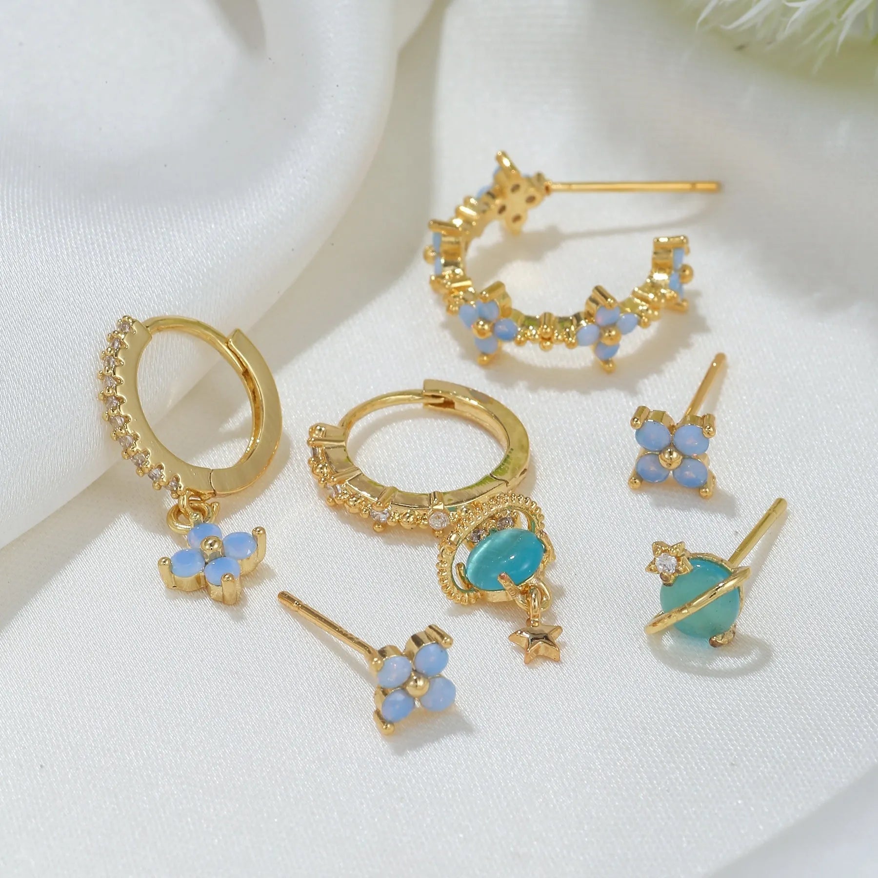 Gold and silver flower-shaped ear studs with blue zircon mosaic decoration.