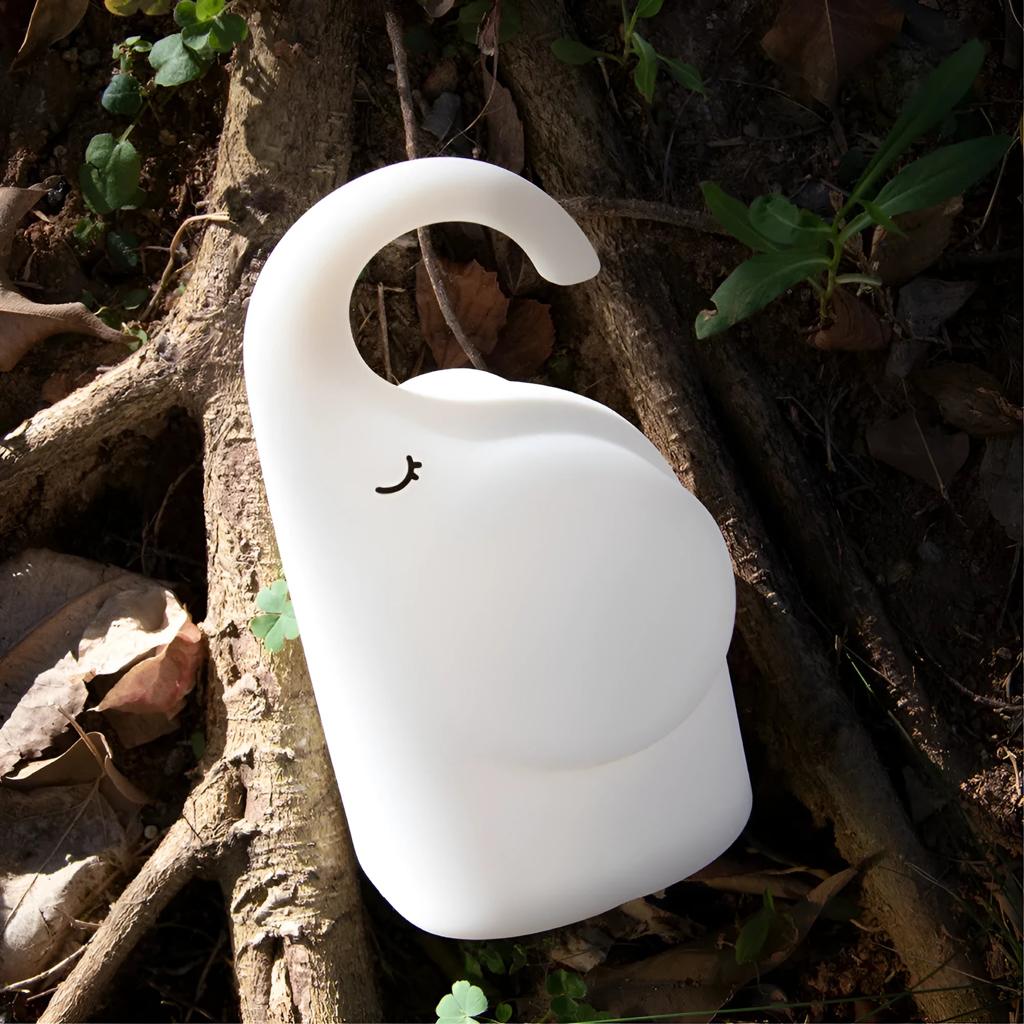 White silicone elephant-shaped night light with a warm glow, placed on a wooden bedside table.