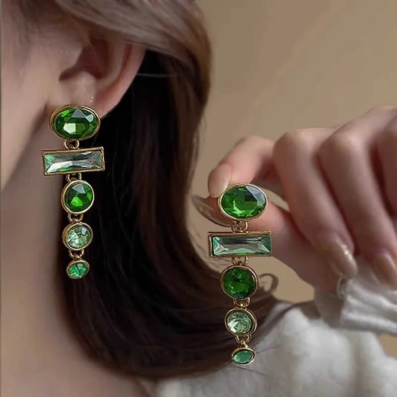 A pair of green gradient geometric drop earrings with inlaid zircon stones and a dangling tassel detail.