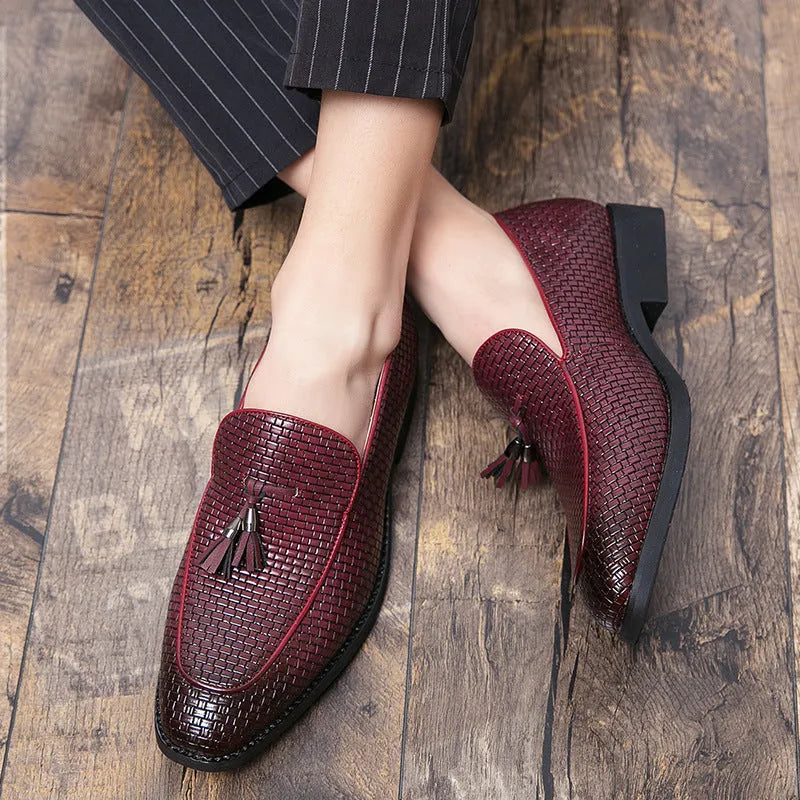 Men's black slip-on leather loafers with a pointed toe and tassel detail on a white background.