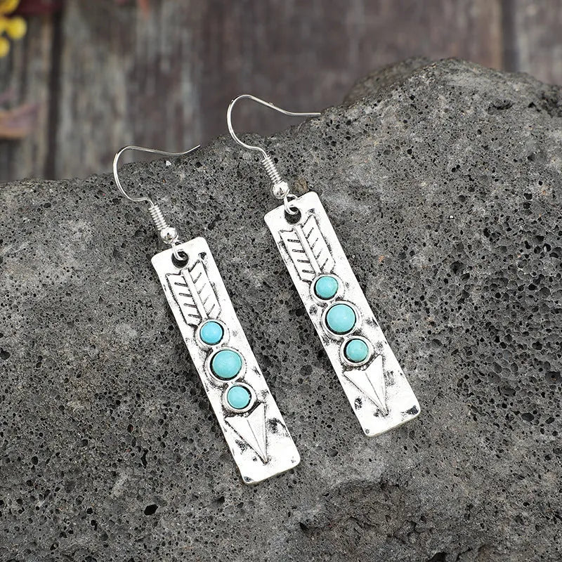 Silver geometric drop earrings with turquoise inlays and retro styling on white background