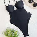 Black solid colour one-piece swimsuit for women on a hanger
