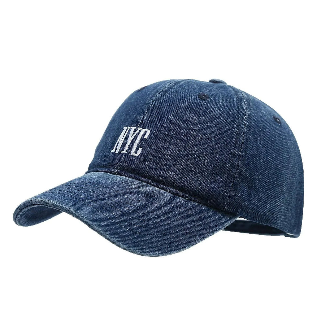 A light blue denim peaked cap with a dome crown, adjustable strap, and decorative white English letters on the front.