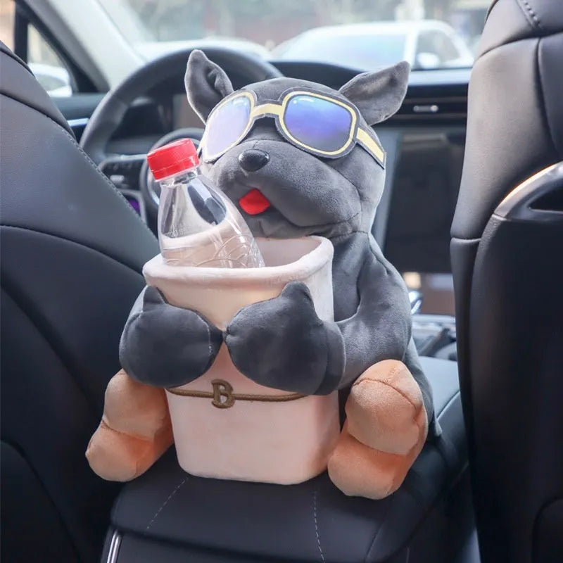 Plush car tissue box holder hanging from flip-down armrest with humorous dog design