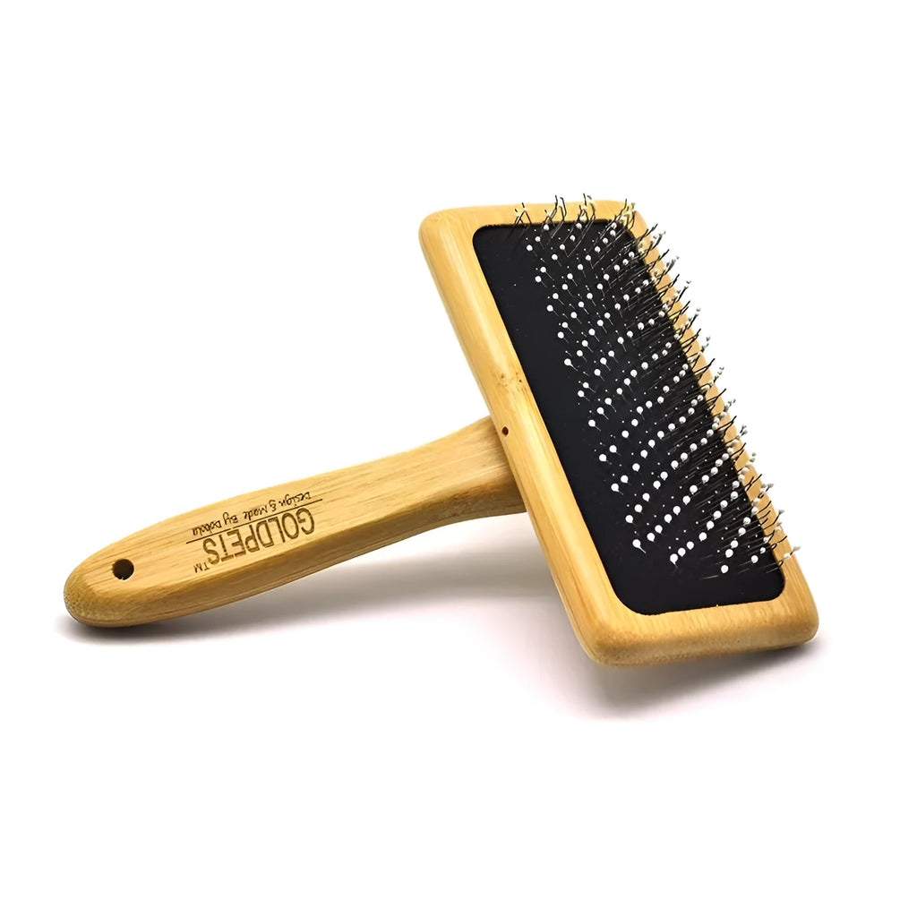 Goldpets bamboo and wood pet slicker brush with stainless steel pins on a wooden table.