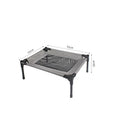 Black Oxford cloth outdoor dog bed with steel frame, shown on grass for camping use.