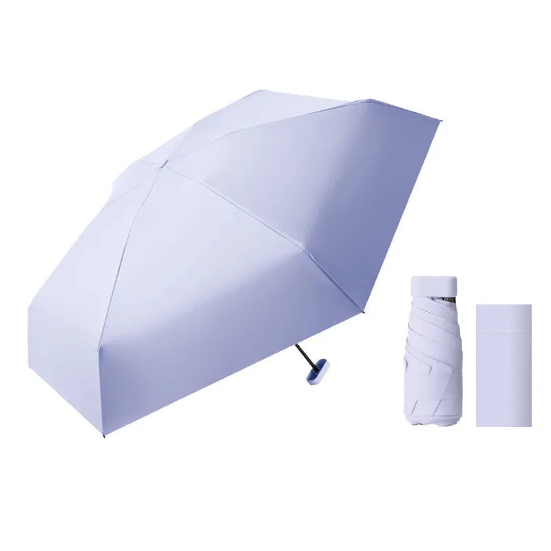 Ultra-light six-fold flat sun umbrella in sky blue with a rubber handle, shown with its capsule storage box.