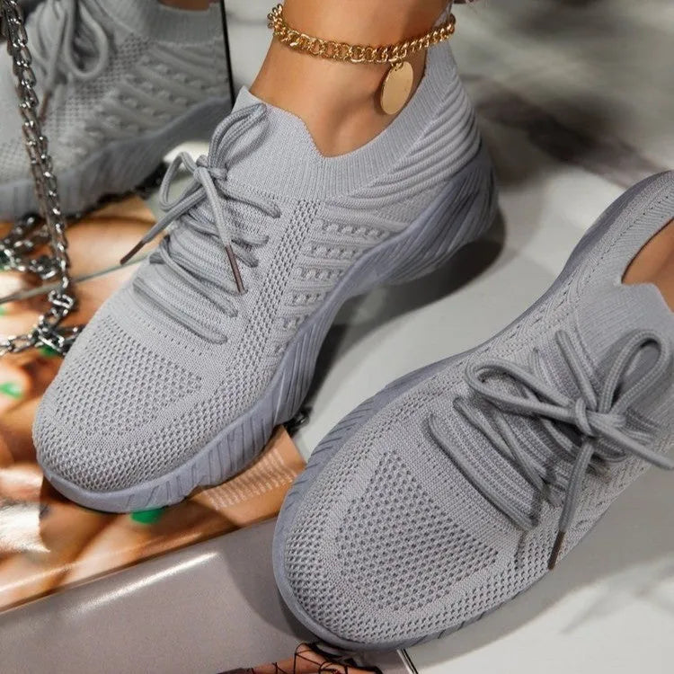 Women's white thick-sole dad-style sports sneakers on a neutral background.