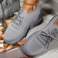 Women's white thick-sole dad-style sports sneakers on a neutral background.