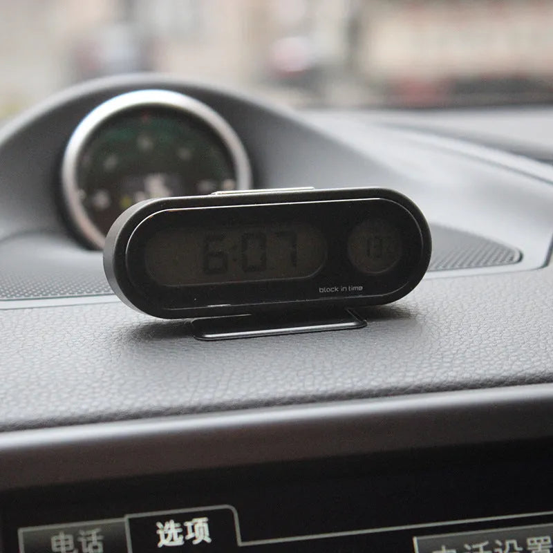 Black electronic car clock and thermometer on an adjustable bracket with luminous LED display.