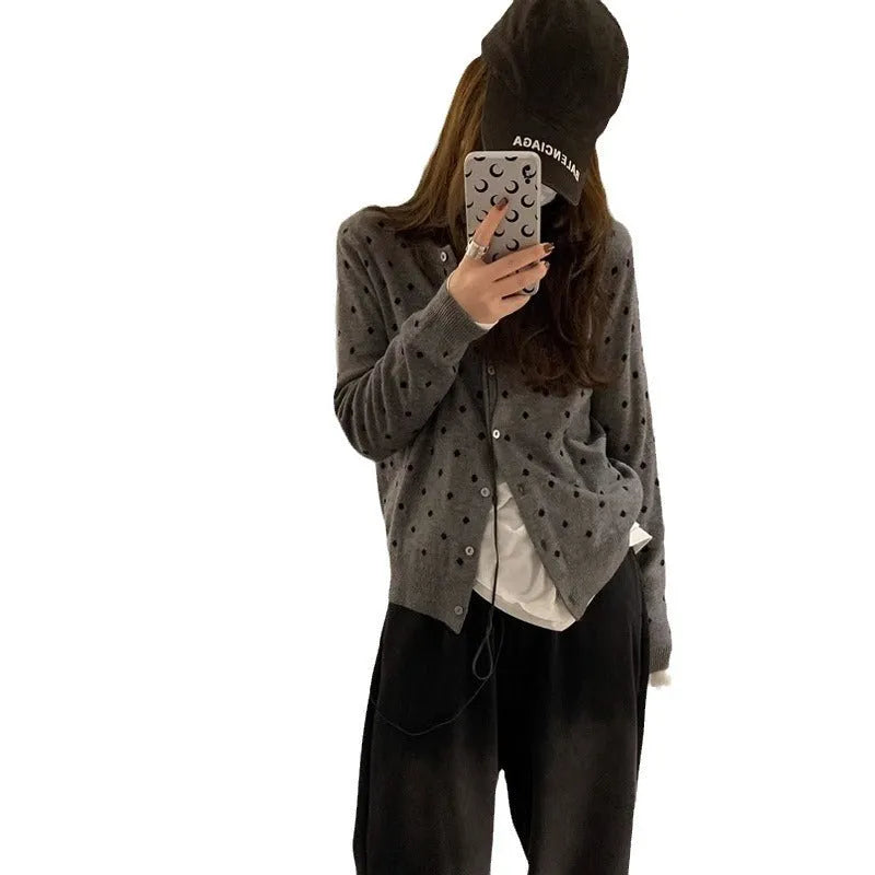 Women's grey dot pattern knitted cardigan with crochet floral detail on the front.