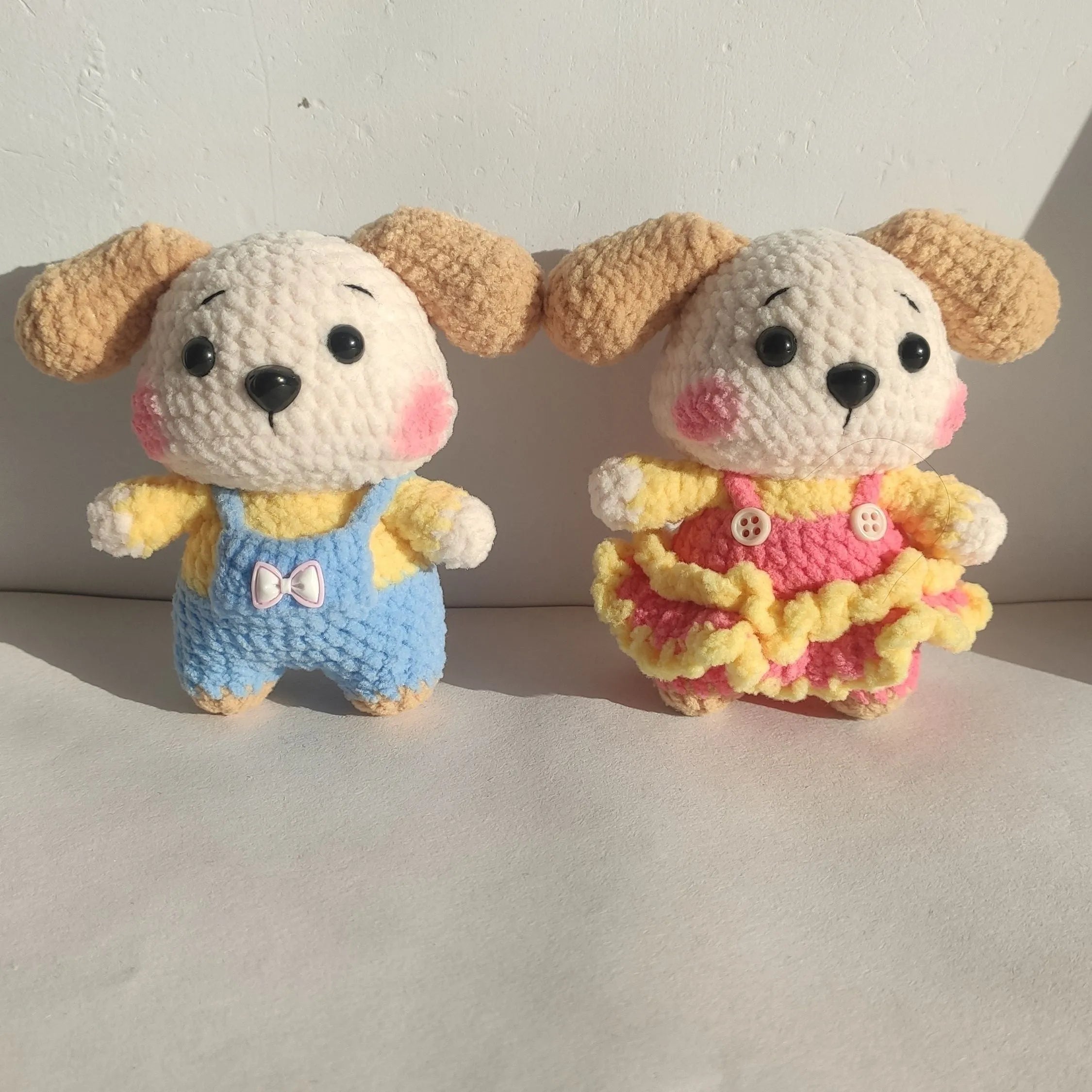 A pair of wool zodiac dog pendant charms on keychains, one wearing a strap skirt and the other strap pants.
