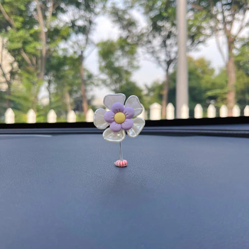 Small blue plastic swing decoration for a car dashboard, shown next to a coin for scale.