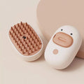 White rechargeable silicone steam brush for grooming dogs and cats on a table.