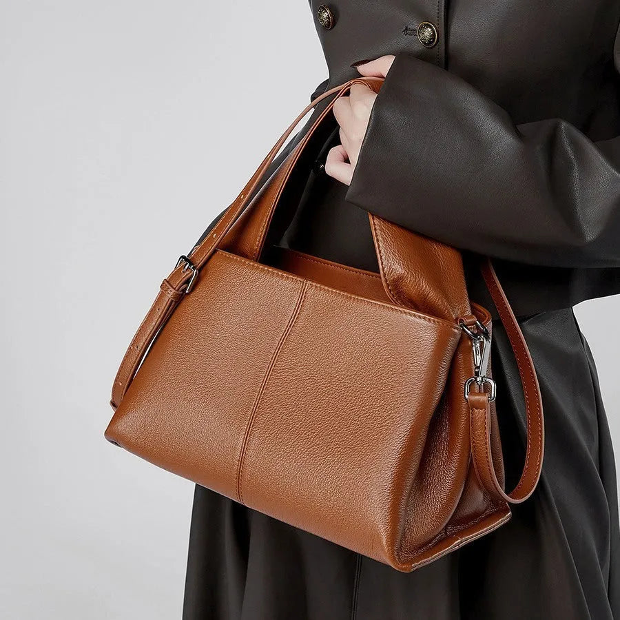 Women's brown retro texture leather messenger bag with a double shoulder strap shown on a table.