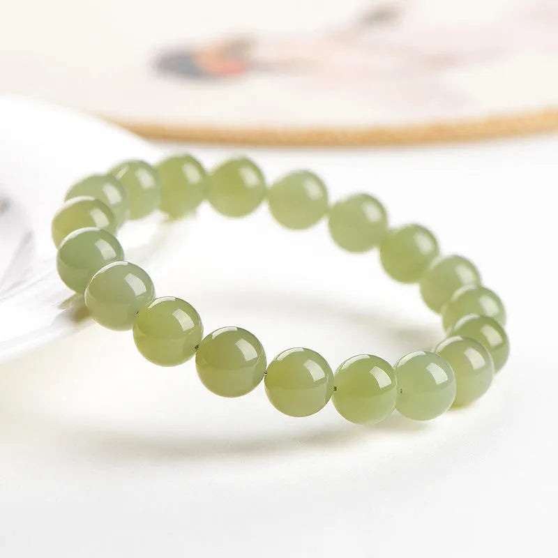Polished Hetian jade ball bracelet showing different bead sizes on a wrist, in clear ice-like colours.