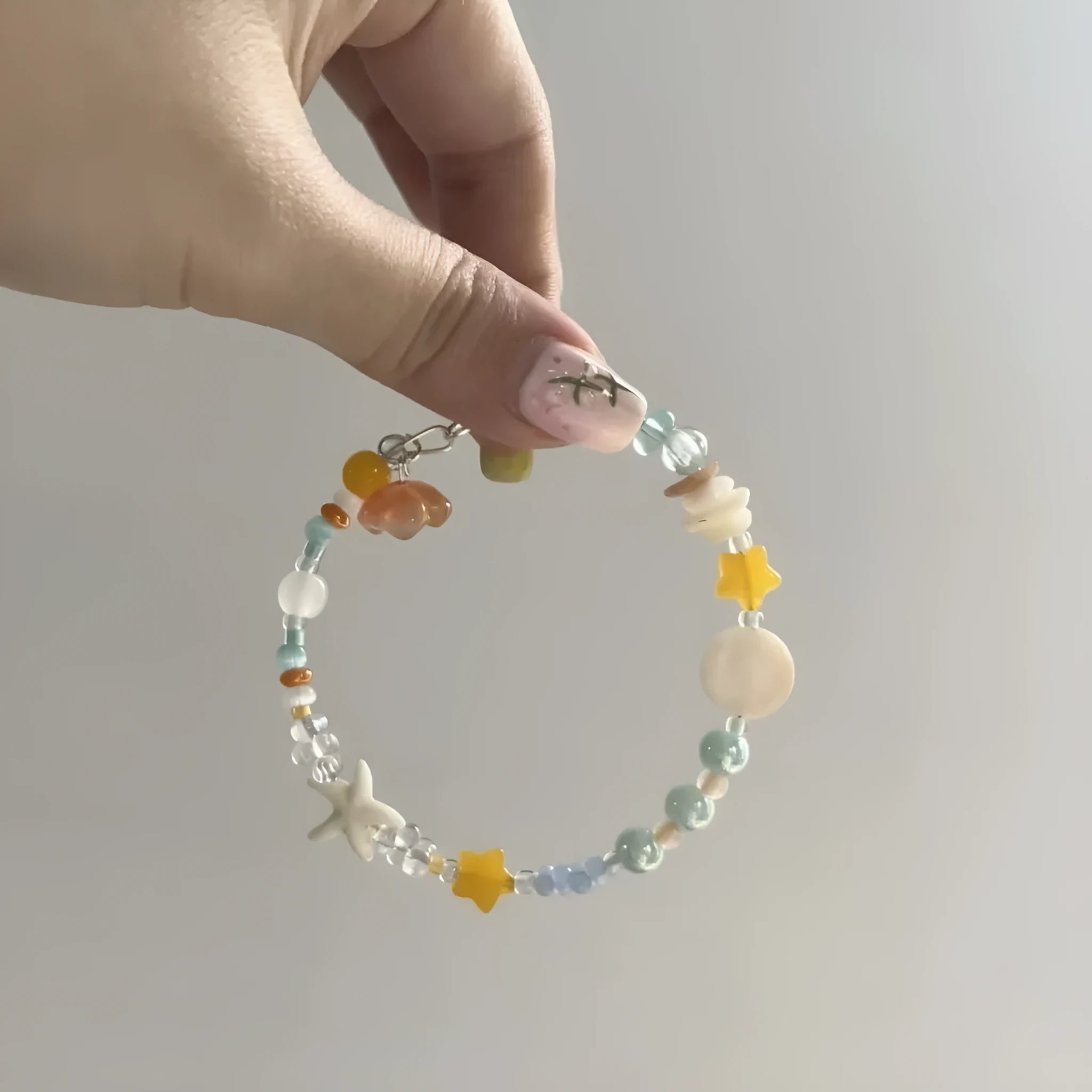 Diamond-shaped mixed-material bracelet for women in orange and sea summer colours with round design elements.