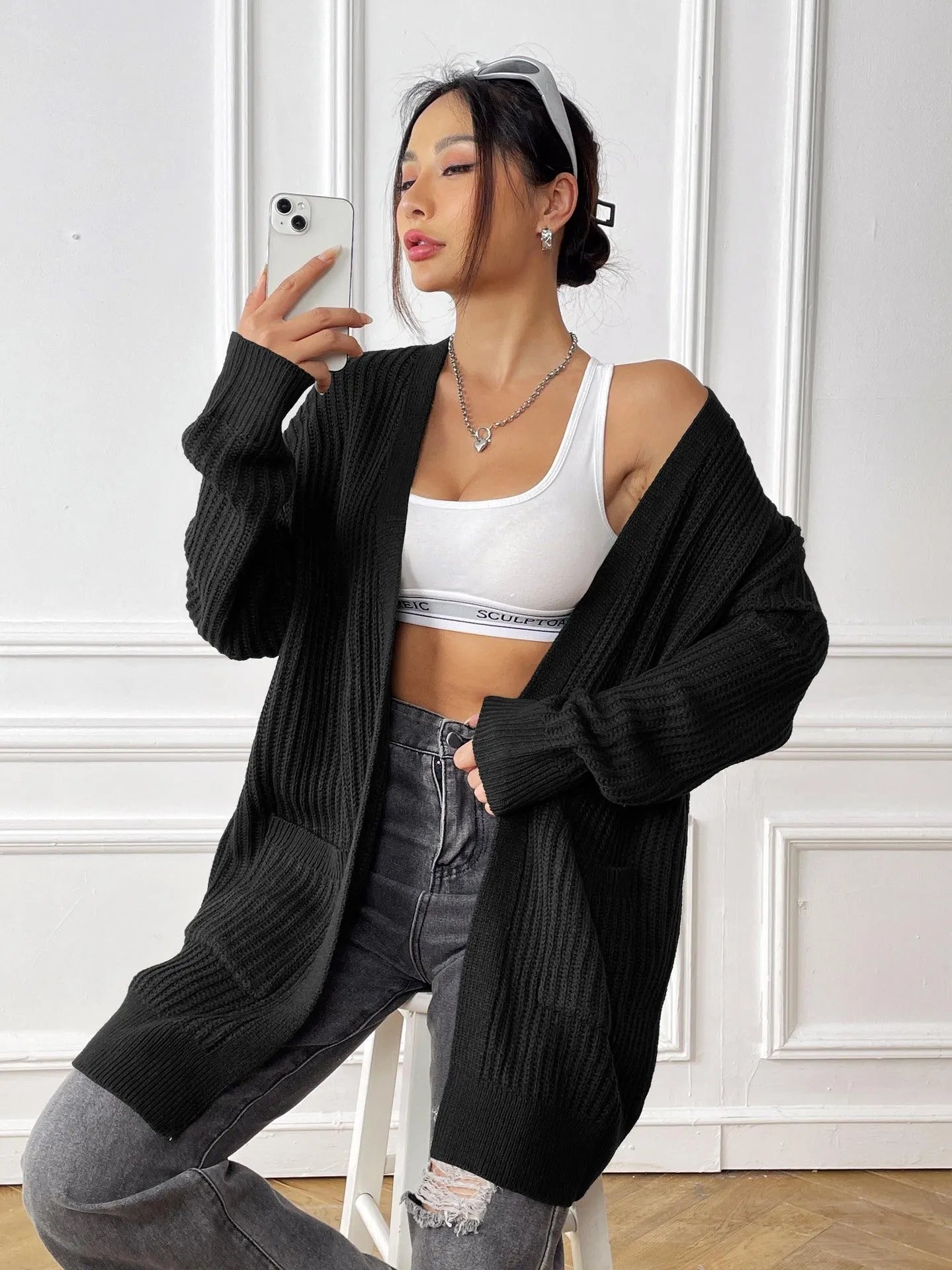 A woman's loose-fit mid-length cardigan in a solid colour, shown on a hanger.