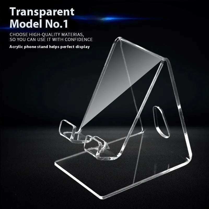 Clear acrylic mobile phone stand on a desk with a smartphone placed in it, showing the universal fit and transparent design.