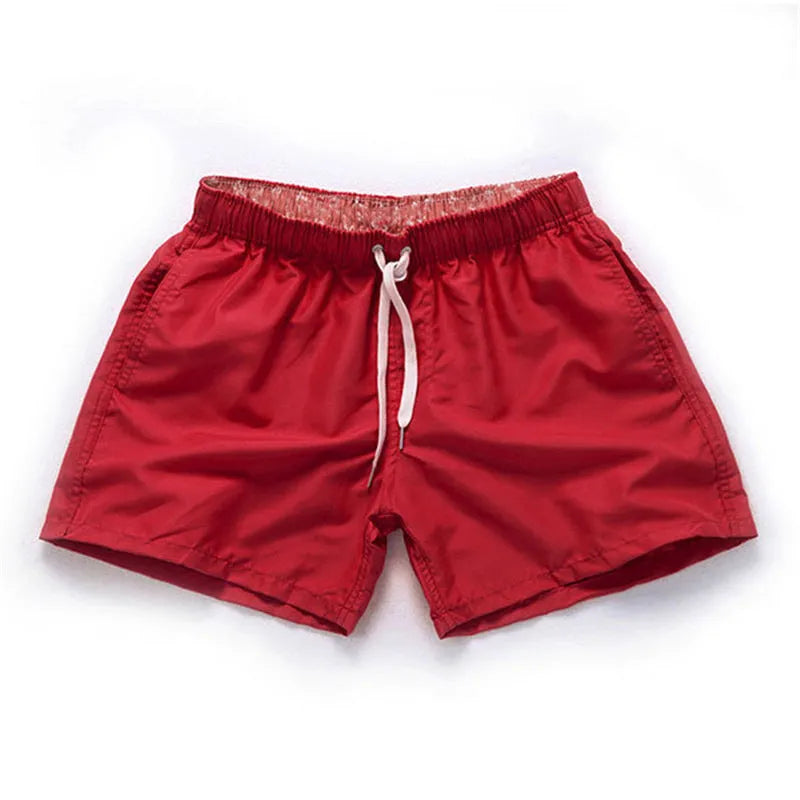 Men's straight-leg polyester surf shorts on a beach, available in multiple colours including fluorescent yellow and black.