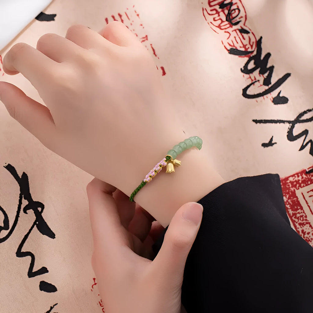 Close-up of a hand-woven red rope bracelet with floral design details on a wrist.