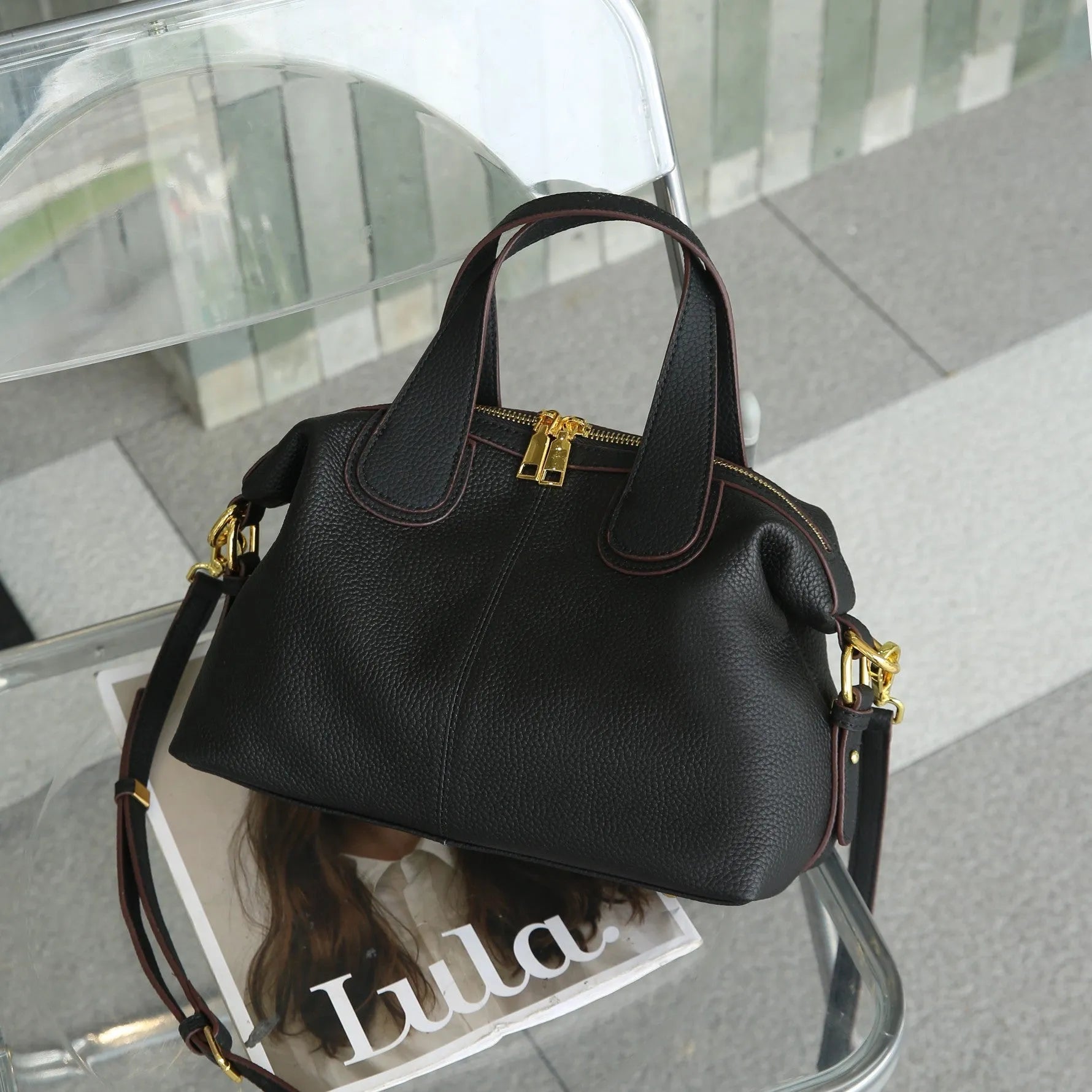 Women's leather cross-body bag in horizontal square shape with visible sewing thread detailing and interior compartments