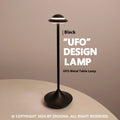 Rechargeable UFO-shaped metal desk lamp in black on a wooden table.