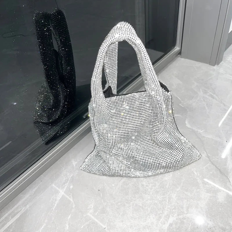 Silver cotton thread evening clutch covered in shiny rhinestones with an open outer pocket and shoulder strap.