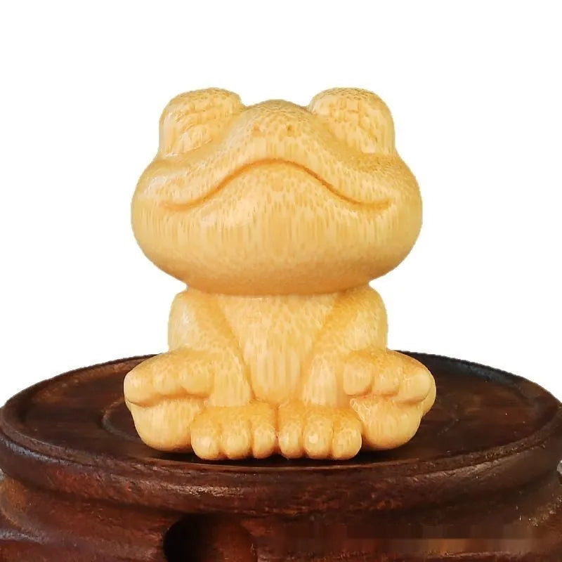 Small smiling frog ornament carved from solid bamboo on a plain background.
