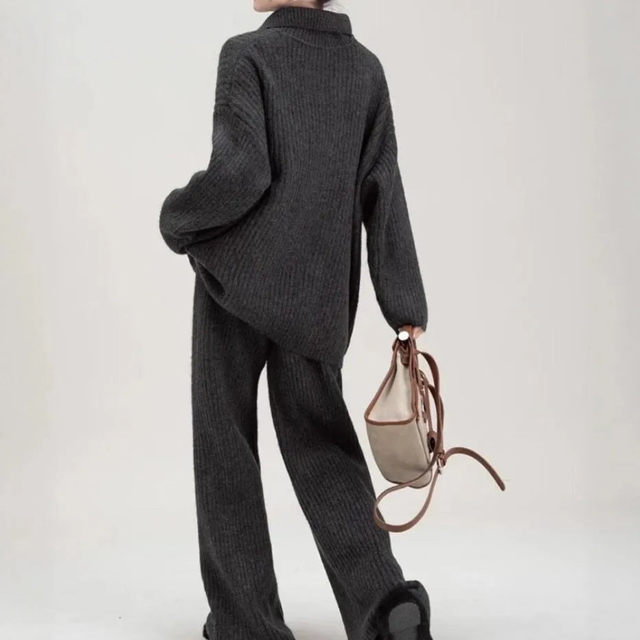 Women's dark grey acrylic knit sweater suit two-piece set with long sleeves and casual trousers.