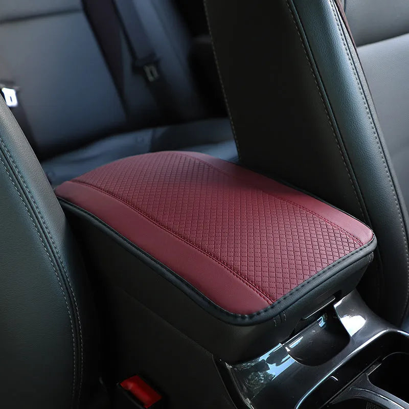 Embossed fibre leather car armrest box cushion measuring 32cm by 19cm in black with red trim