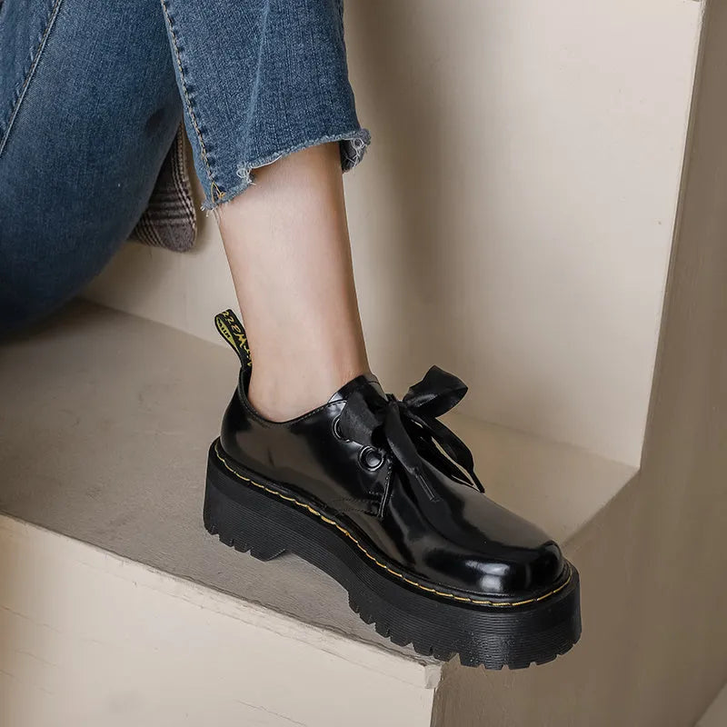 Black and white women's lace-up shoes with a thick sole, cross straps, and ribbon details.