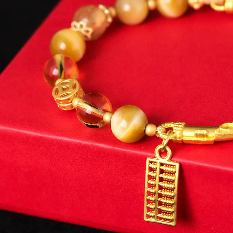 Close-up of handmade abacus bracelet with tigereye, citrine, and yellow tower crystal beads in a diamond shape on a wrist.