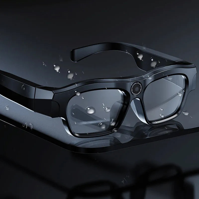 Black smart Bluetooth glasses with a built-in camera lens on the frame, shown with charging cable and case.