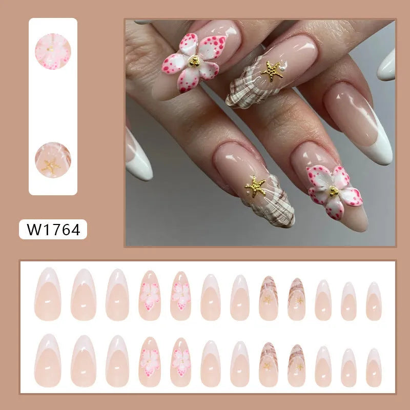 French style false nails with white tips and a black rock pattern patch featuring simple pink and white flowers.