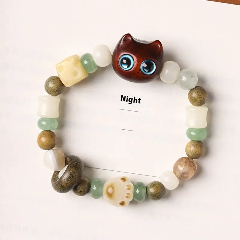 Hand-woven bracelet with bodhi seeds, jade, and wood featuring cartoon cat charm in multiple colour options